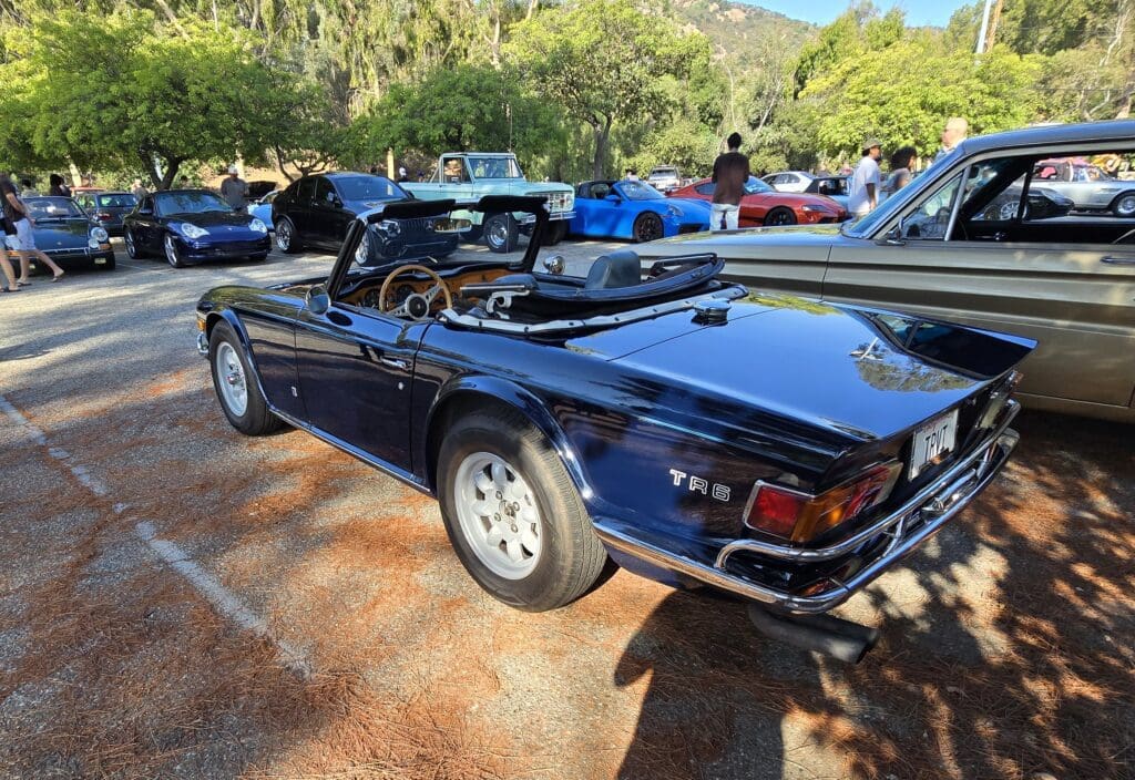 Classic black convertible sports car parked outdoors on a sunny day.