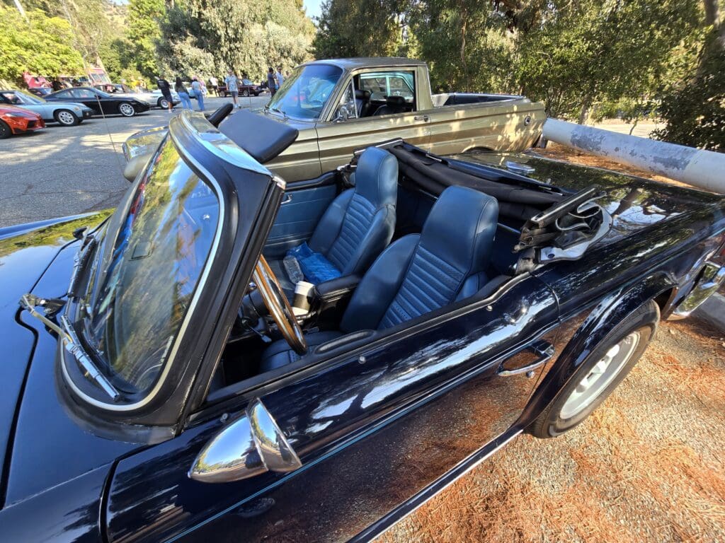 Classic convertible car with black leather interior and wooden steering wheel.