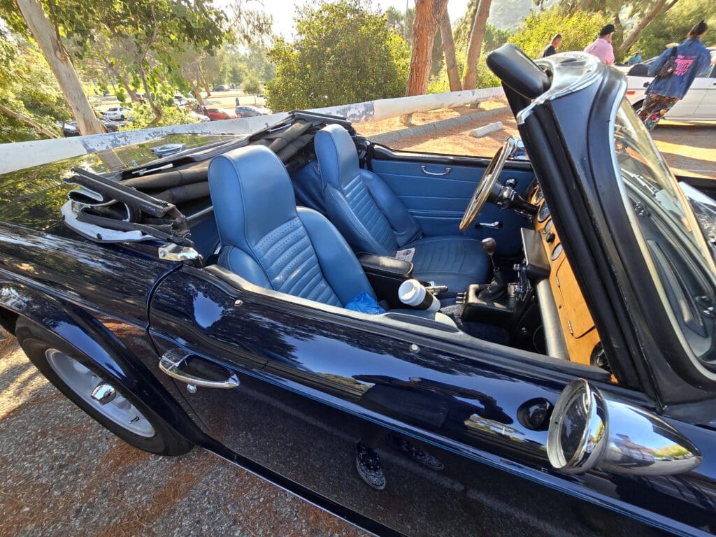 Classic convertible car with blue leather seats and a sleek black exterior.