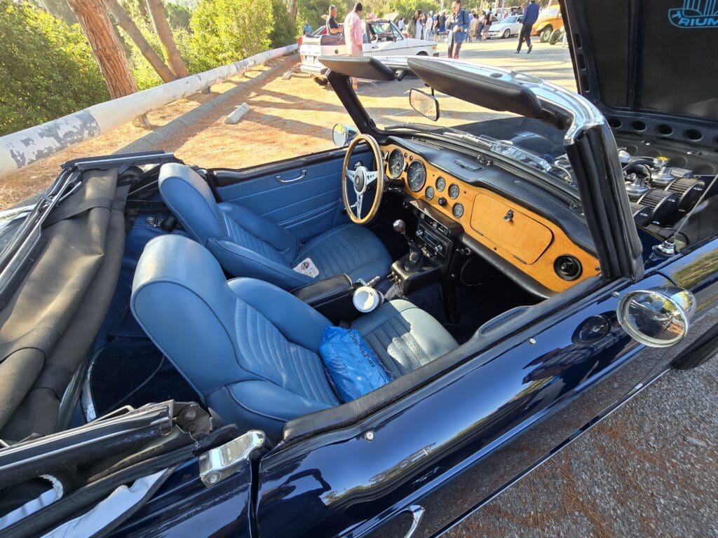 Classic convertible car with blue leather seats and wooden dashboard.