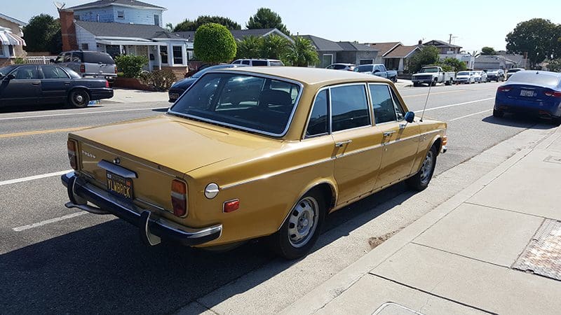 Classic yellow vintage car parked on a sunny street.