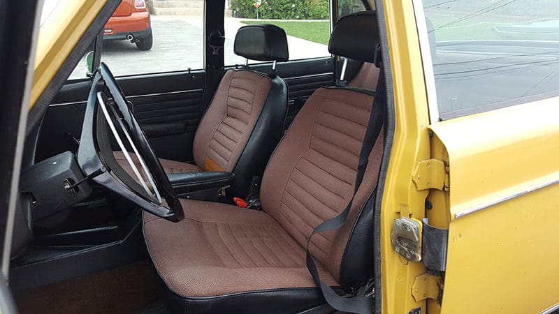 Interior of a yellow vintage car showcasing brown leather seats.