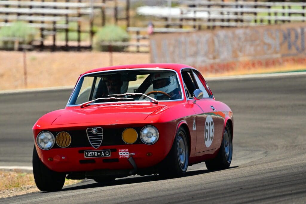 Classic red Alfa Romeo racing car speeding on a track.