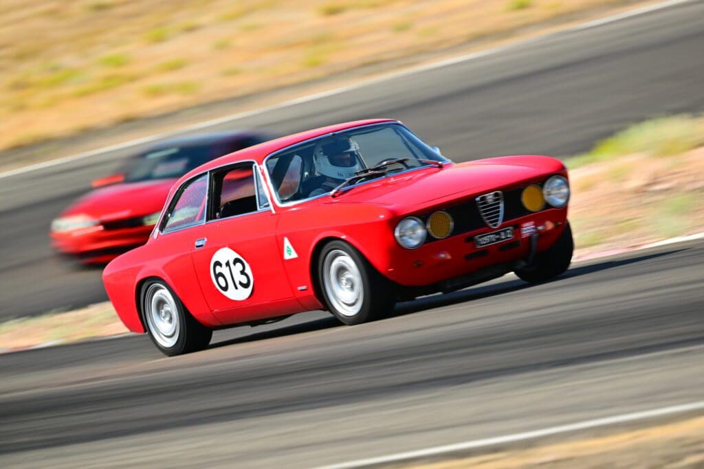 Classic red race car speeding on a track during a race.