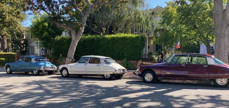 Two classic cars parked on a sunny residential street.