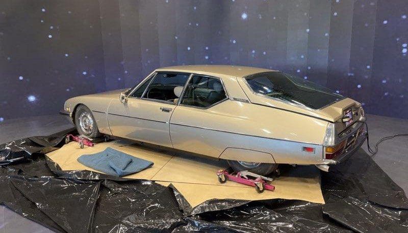 Vintage cream-colored car on display with starry backdrop.