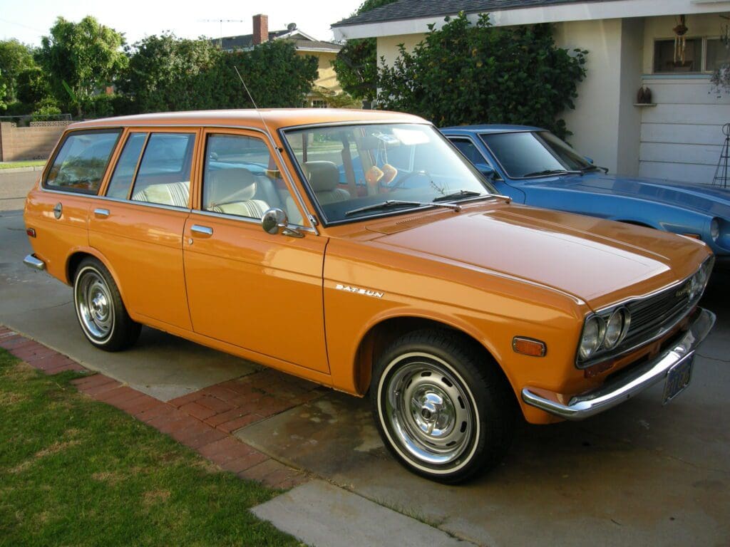 A vintage orange station wagon parked in a driveway.