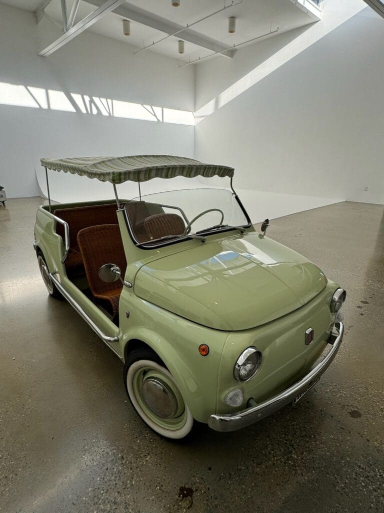 Vintage Fiat 500 with an open roof in a bright showroom.