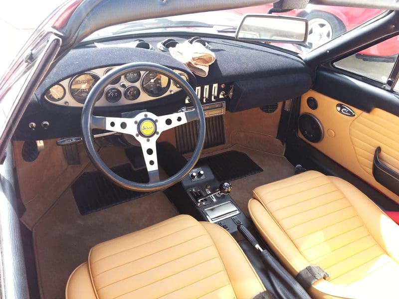 Interior of a classic car with tan leather seats and a black dashboard.