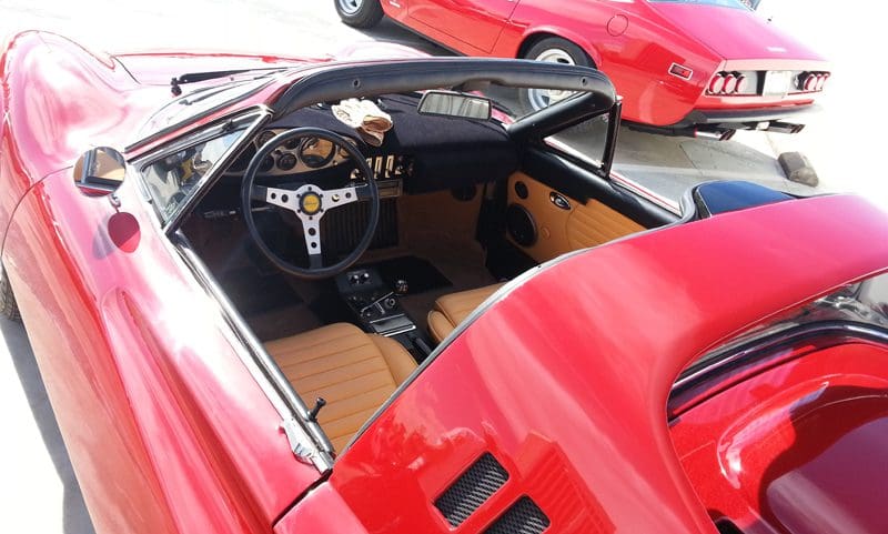 Interior of a classic red sports car with tan leather seats and a vintage steering wheel.