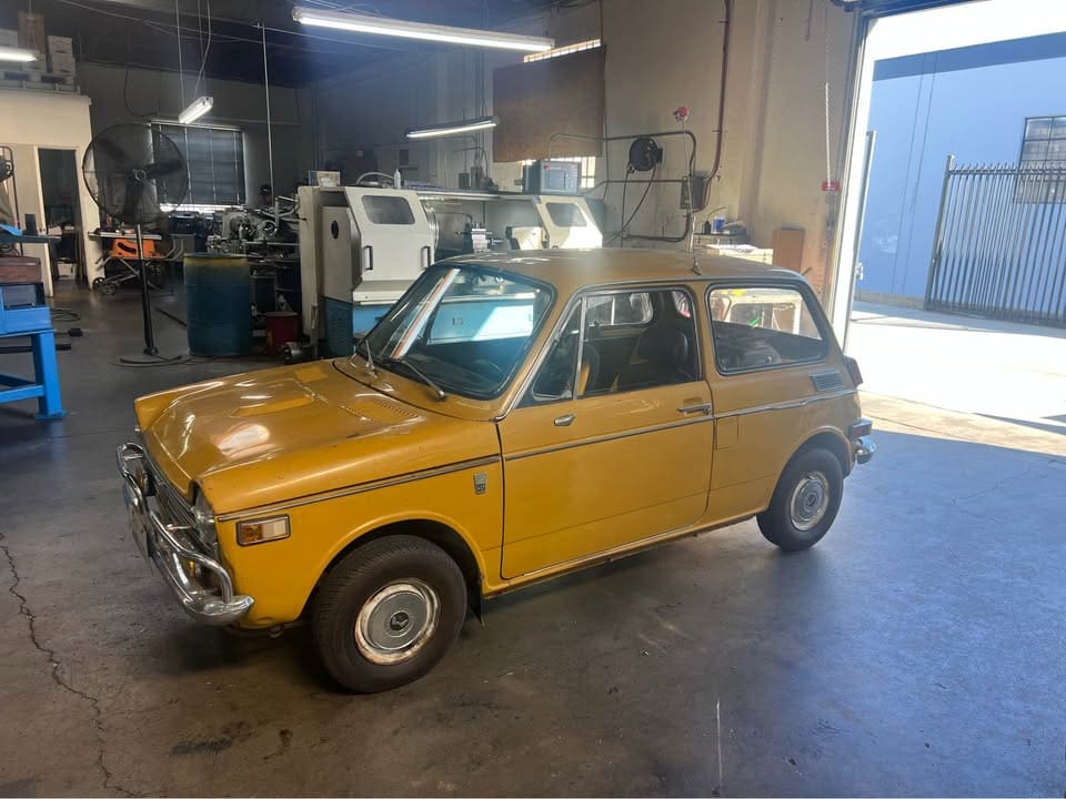 A vintage yellow car parked indoors in a workshop.