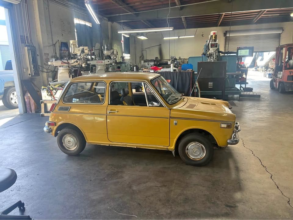Vintage yellow car parked inside a workshop.