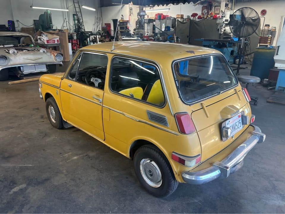 A vintage yellow hatchback car parked inside a garage.