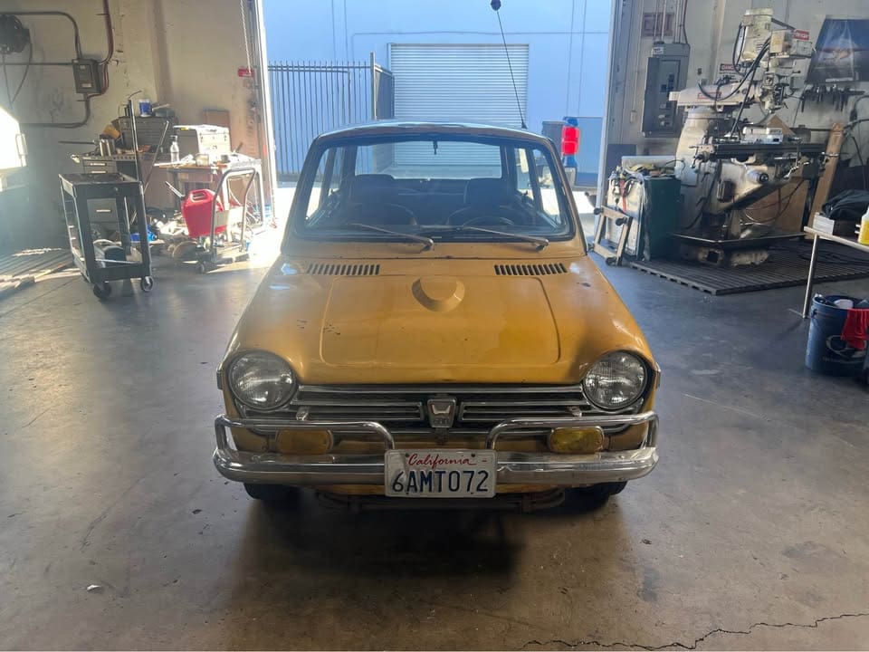 Vintage yellow car parked inside a garage or workshop.