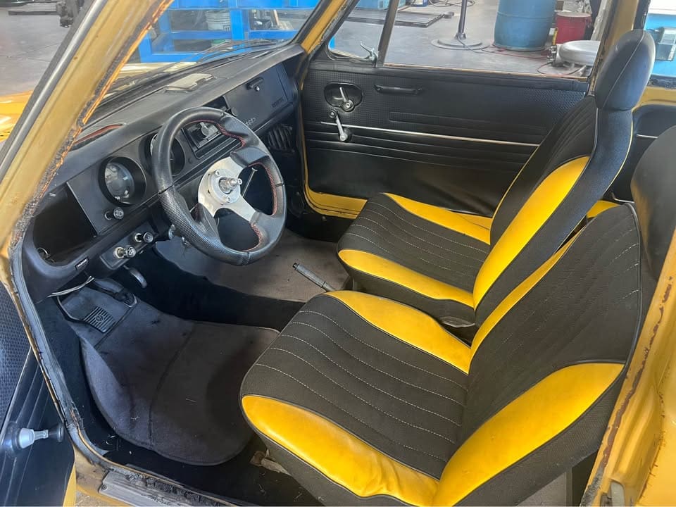 Interior of a car with custom black and yellow seats and a sporty steering wheel.