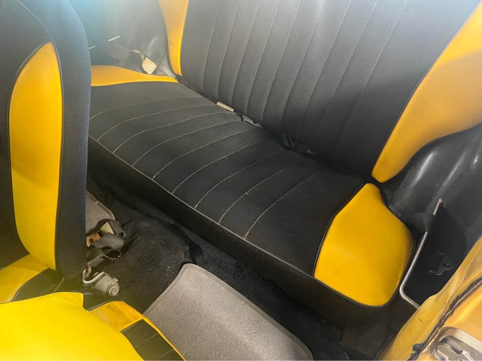 Black and yellow car backseat with a set of keys on the floor.