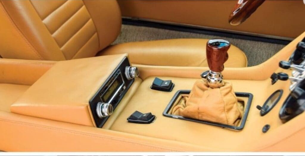 Close-up of a classic car's leather interior with gear shift and controls.
