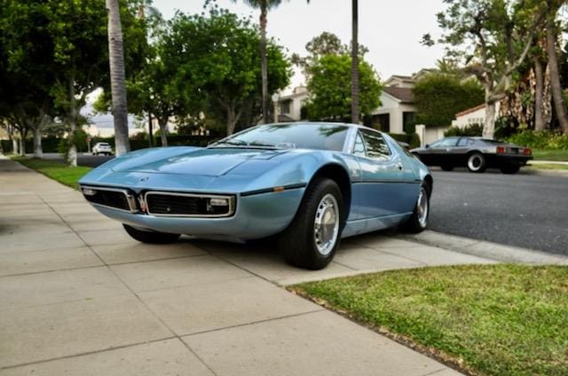 A vintage blue sports car parked on a suburban street.