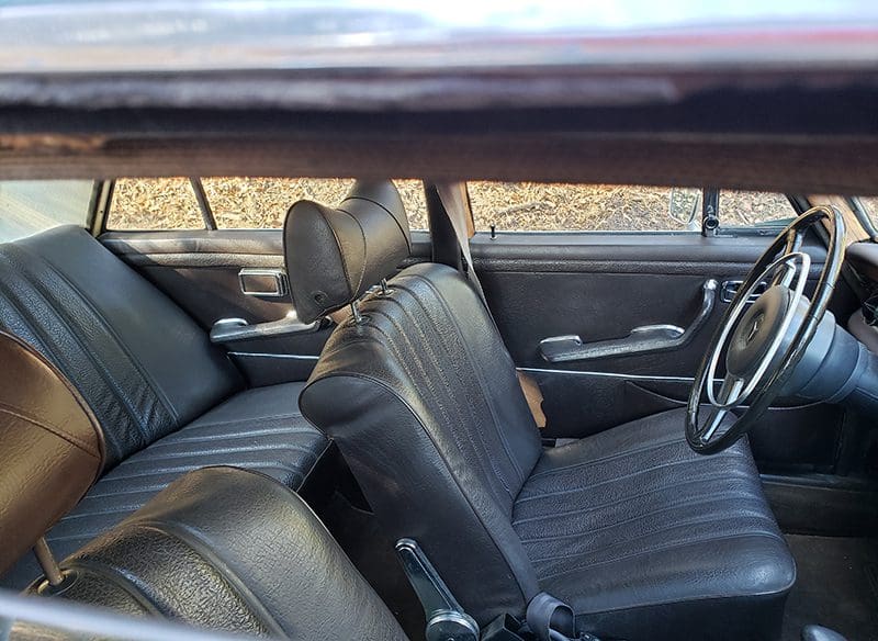 Interior view of a vintage car with black leather seats.