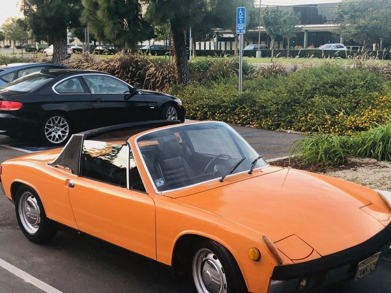 Bright orange classic convertible car parked outdoors.