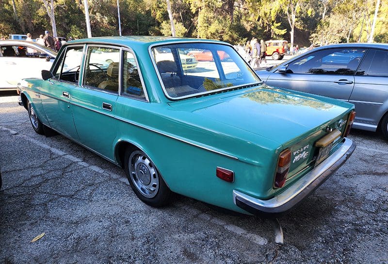 A vintage teal station wagon parked outdoors on a sunny day.