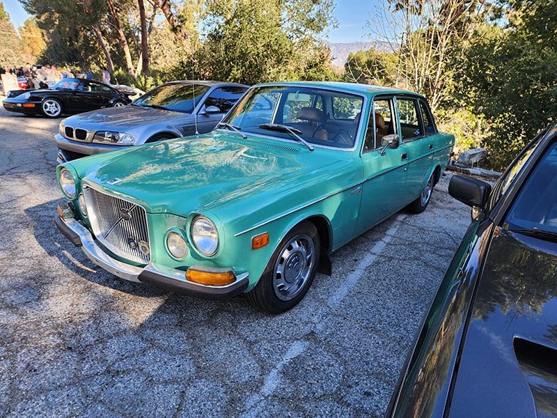 Vintage turquoise Volvo parked in a sunny outdoor lot.
