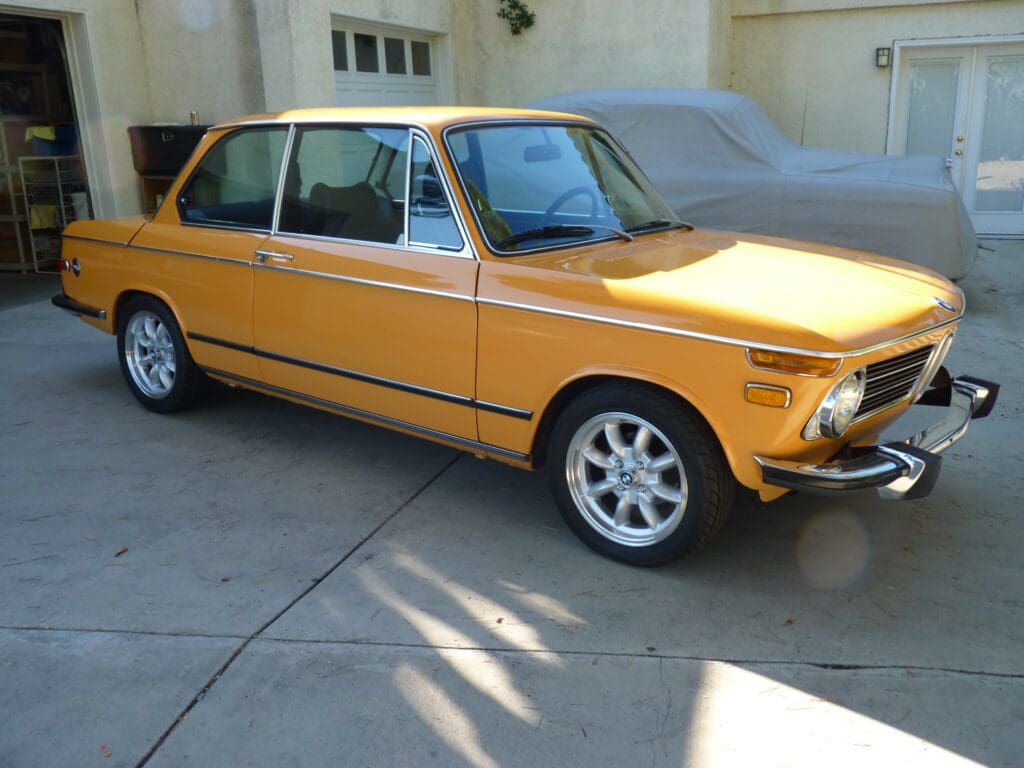 Yellow vintage hatchback car parked in a driveway.