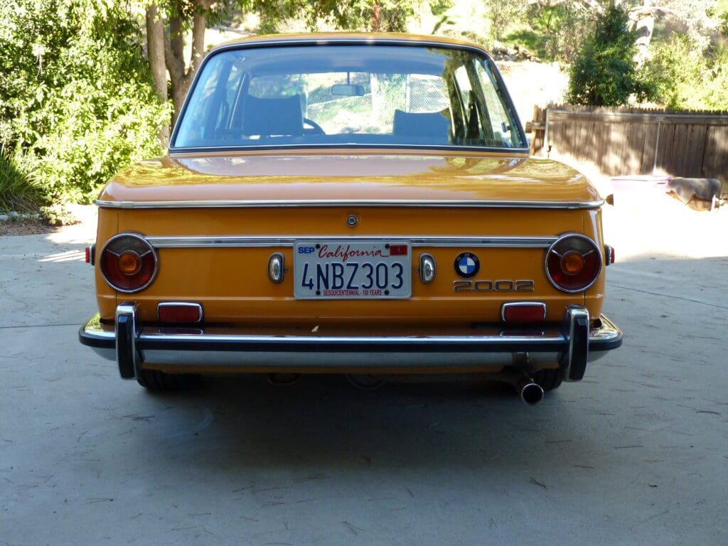 Rear view of a vintage yellow car with a California license plate.