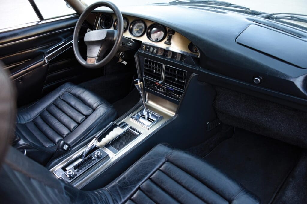 Interior of a classic car with black leather seats and a vintage dashboard.
