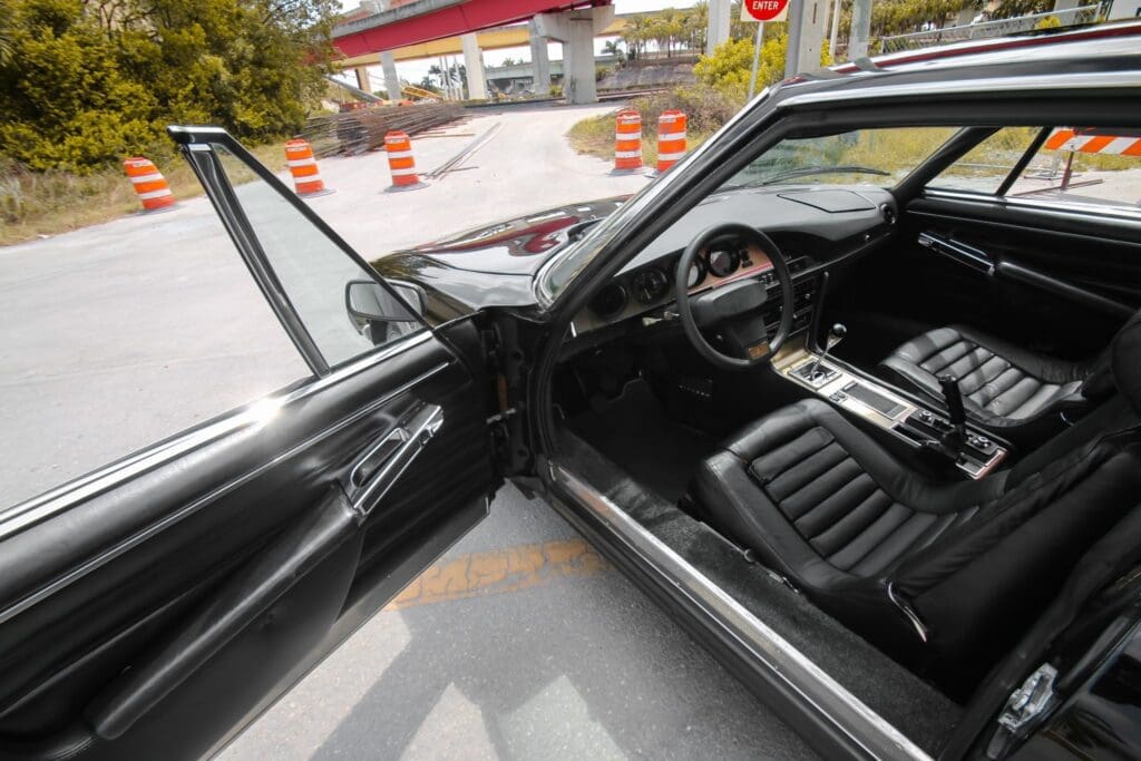 Interior view of a classic car with the driver's door open.