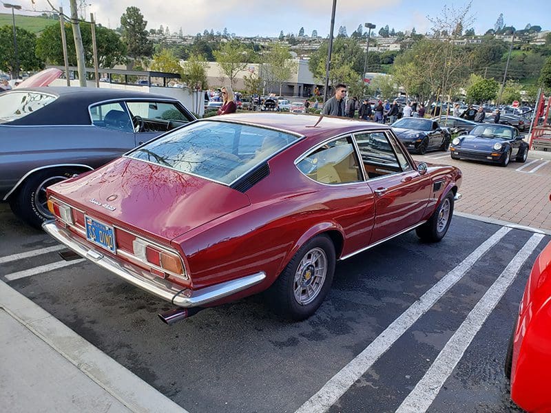 Classic red vintage car parked outdoors near a building.
