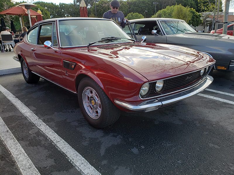 Classic red vintage car parked outdoors on a sunny day.