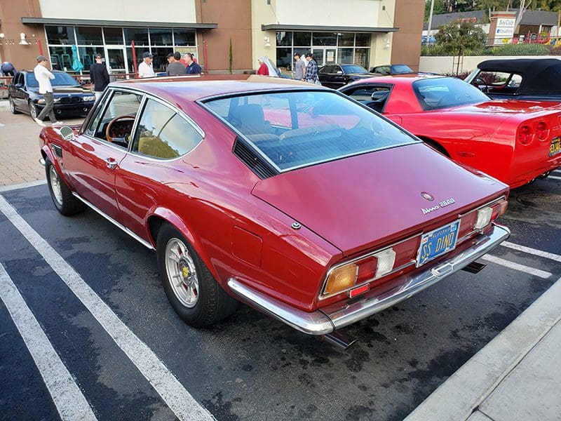 Classic red vintage car parked outdoors on a sunny day.