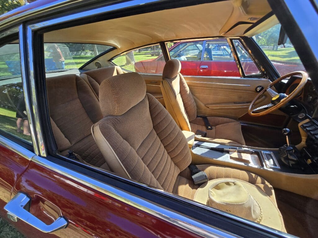 Interior view of a classic car with plush tan seats and vintage detailing.