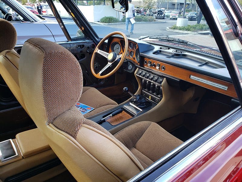 Interior of a classic car with wooden dashboard and brown upholstery.
