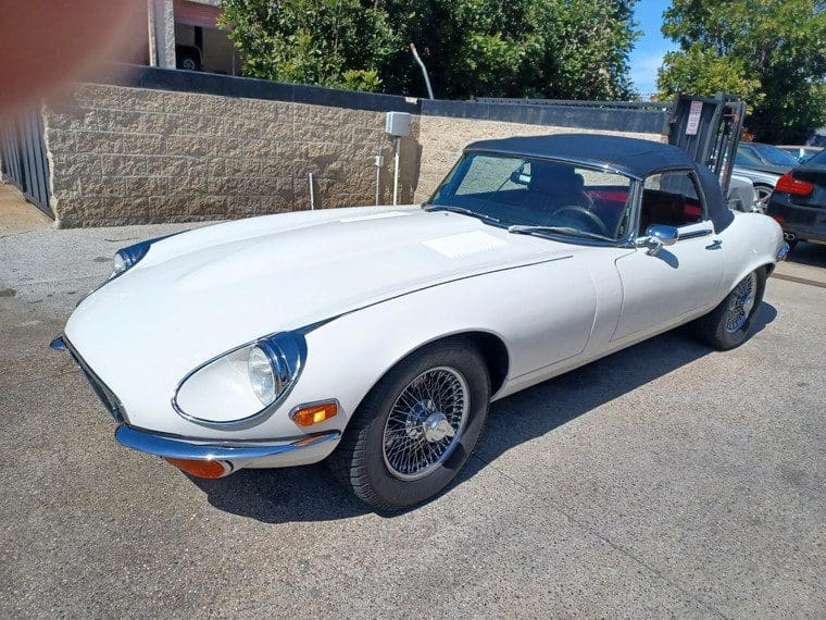 Classic white Jaguar E-Type parked outdoors on a sunny day.