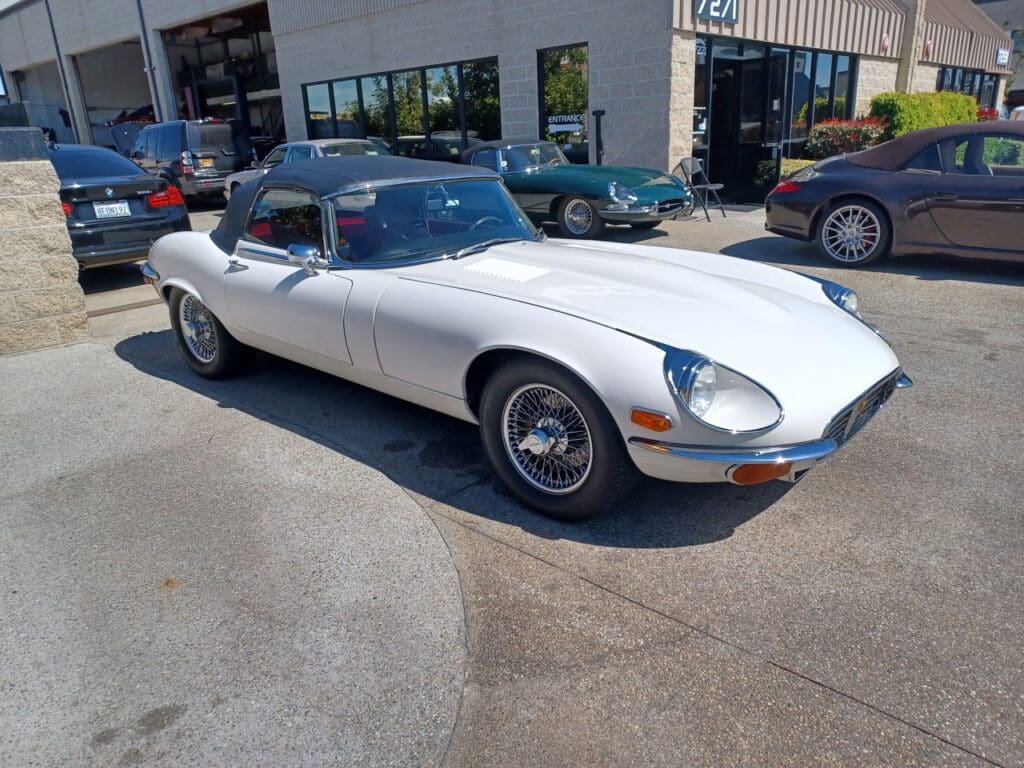 Classic white convertible sports car parked outside a building.
