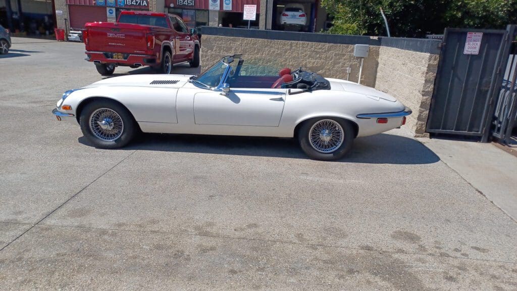 White vintage convertible car parked on a street.