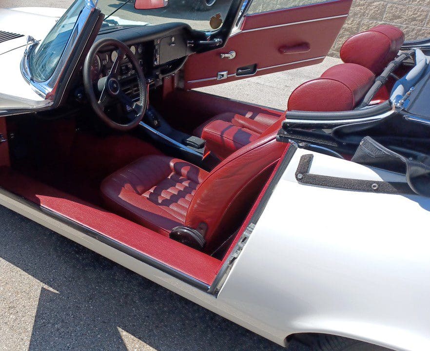 Interior of a classic white convertible sports car with red leather seats.