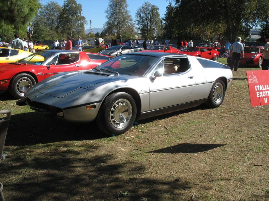 A silver vintage sports car parked on grass at a car show.