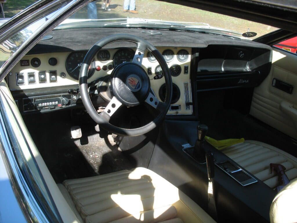 Classic car interior with vintage steering wheel and dashboard.