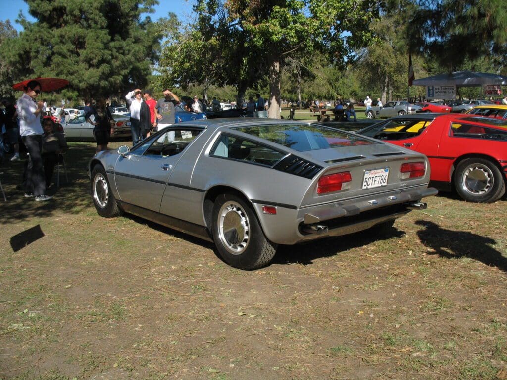 Classic silver sports car parked outdoors on grass.