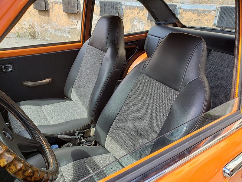 Interior view of a vehicle showing front seats and part of the dashboard.