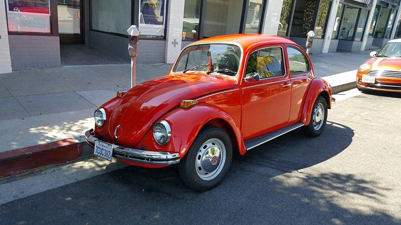 Classic red Volkswagen Beetle parked on the street.
