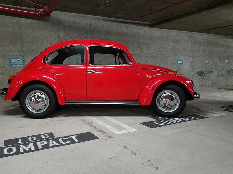 A classic red Volkswagen Beetle parked in a garage.