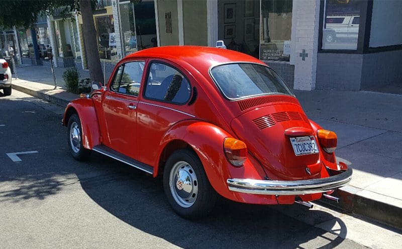 A bright red vintage Volkswagen Beetle parked on the street.