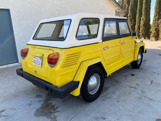 Yellow vintage off-road vehicle with a white canopy parked outdoors.
