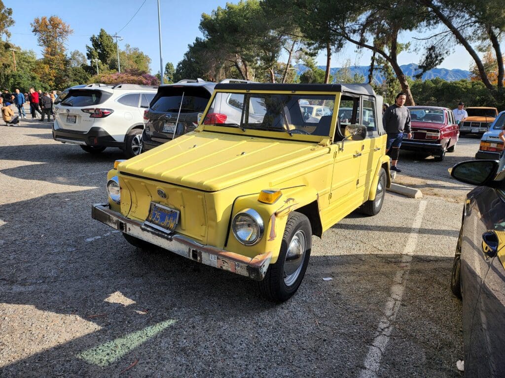 Yellow vintage car parked in a sunlit lot.