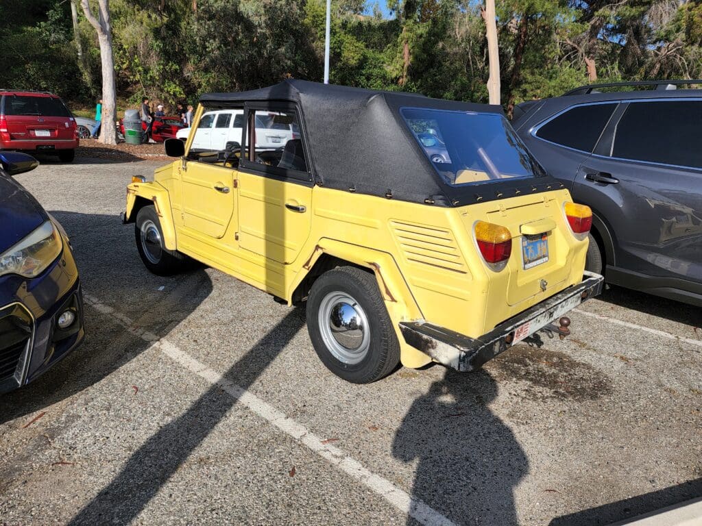 Yellow vintage convertible car parked outdoors in sunlight.