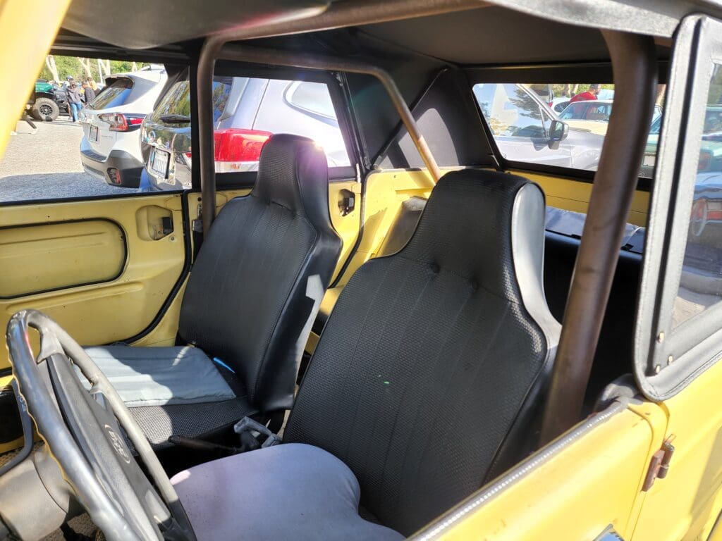Interior view of a yellow sports car with black racing seats and roll cage.